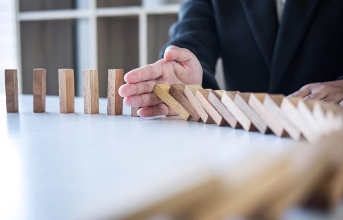 Hand stopping falling wooden dominoes