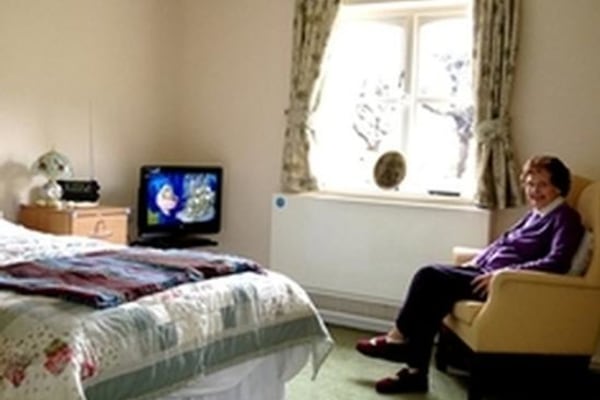 Elderly woman sitting in bedroom armchair