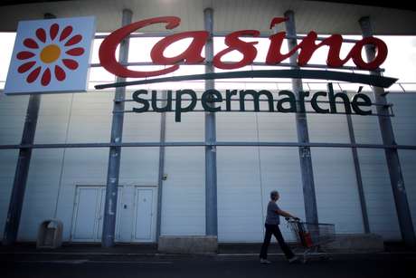 Shopper pushing cart past Casino supermarket