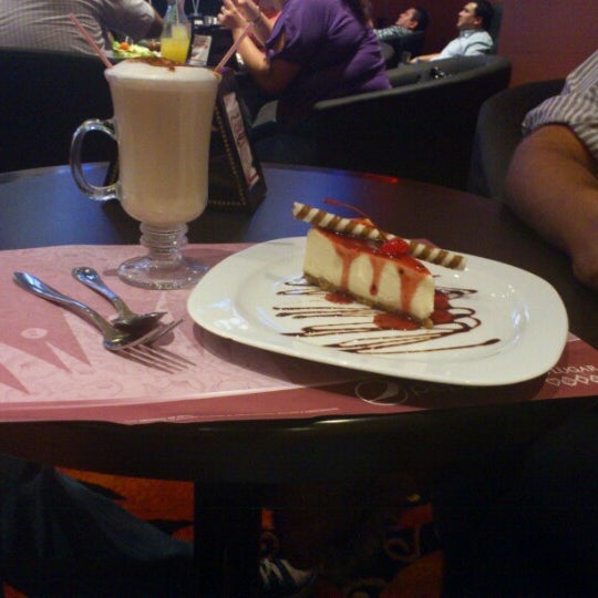 Strawberry topped cheesecake with milkshake on table
