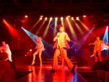 Performer and dancers on red-lit stage