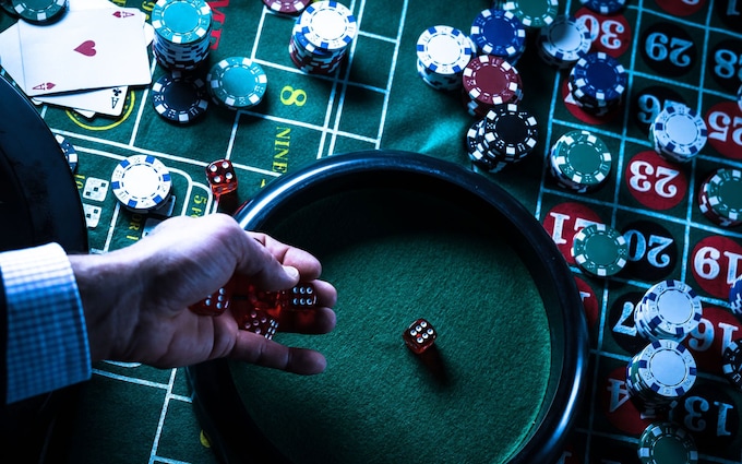 Hand rolling dice on casino table with chips