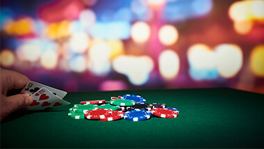 Hand holding cards with poker chips on table